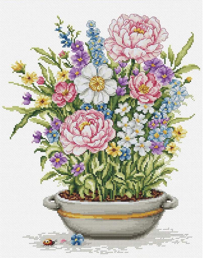 A cross-stitch style floral design featuring pink peonies, white daisies, blue delphiniums, purple forget-me-nots, and yellow wildflowers arranged in a white planter with a gold stripe, on a white background.
