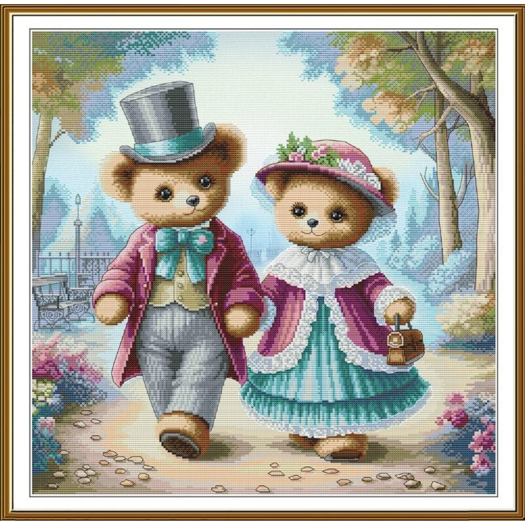 A framed cross-stitch or needlework-style artwork showing two teddy bears walking hand in hand along a path. The bear on the left wears a gray top hat, pink jacket, and blue bow tie; the bear on the right wears a pink hat with flowers, a pink and teal dress, and holds a small bag.