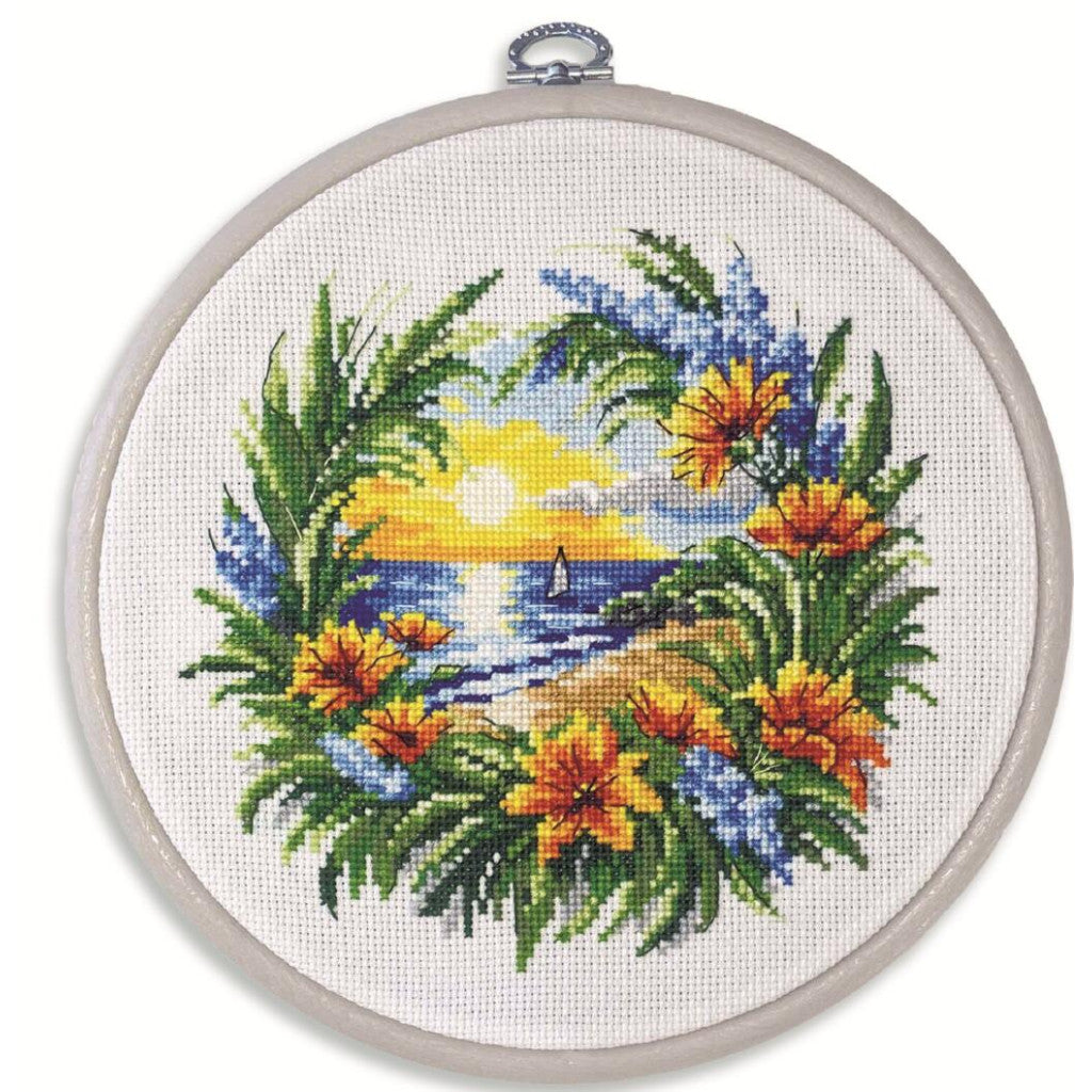 Cross-stitched tropical scene with flowers and a sunset in an embroidery hoop.