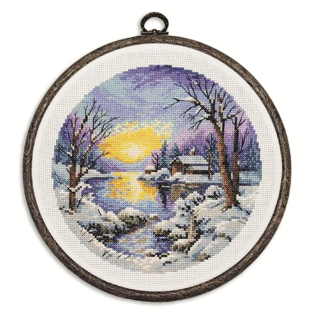 Cross-stitched winter scene with a moonlit sky and snow-covered landscape in an embroidery hoop.