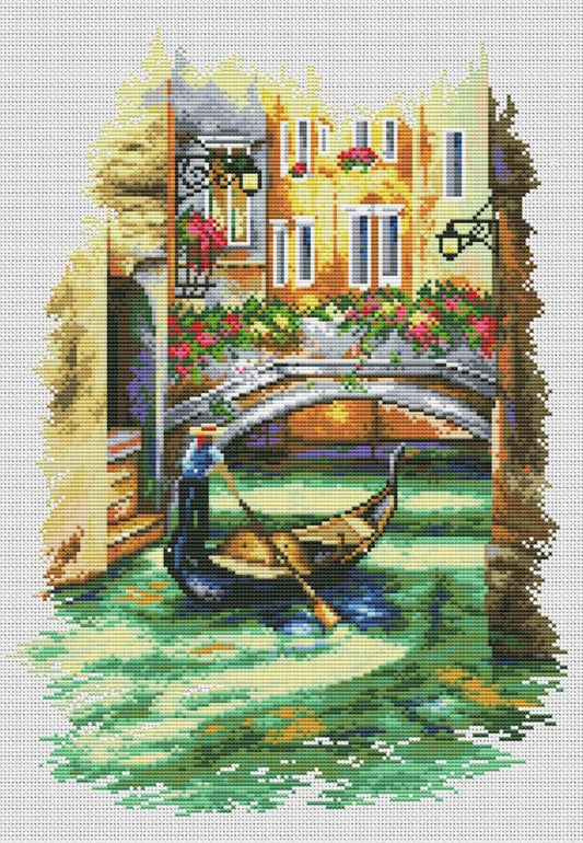 Cross-stitched scene of a gondolier in Venice with a canal and buildings.