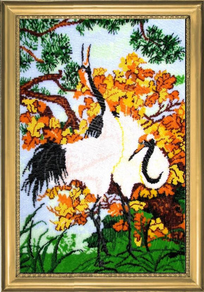 A bead embroidery kit depicting white cranes among orange and green foliage, with a printed pattern on fabric, beads, and a needle included.