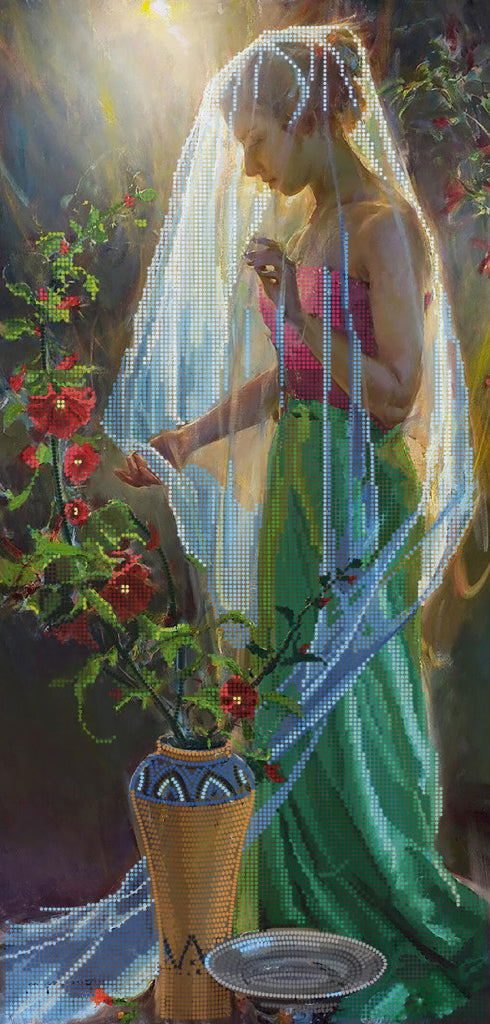 Woman in a green dress with a veil, standing next to a vase of flowers, with a blurred background.