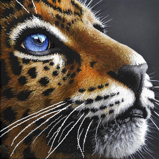 Close-up of a embroidered or painted leopard's face with detailed fur and blue eye.
