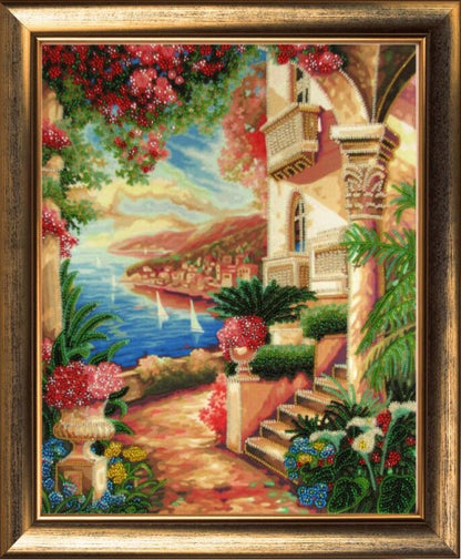 A bead embroidery kit depicting a vibrant scene with flowers, buildings, and a coastal landscape, framed in a wooden frame.