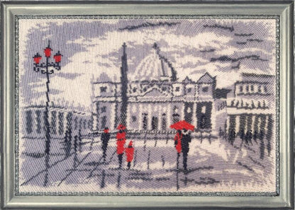 A bead embroidery kit depicting a cityscape with buildings and a person with a red umbrella, presumably the work included in the kit.