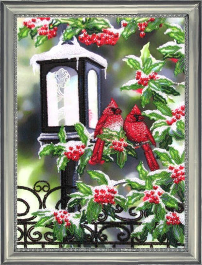A bead embroidery kit depicting red cardinals perched on a fence with green leaves and red berries, and a lantern in the background.