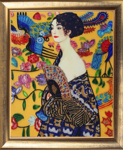Embroidered artwork of a woman in a decorative dress with floral and peacock designs on a yellow background.