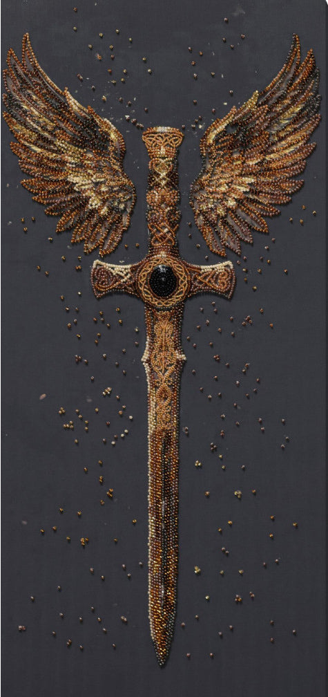 A winged sword design with outstretched golden-brown wings and a central dark gem, shown on a dark textured background with scattered small gold specks.