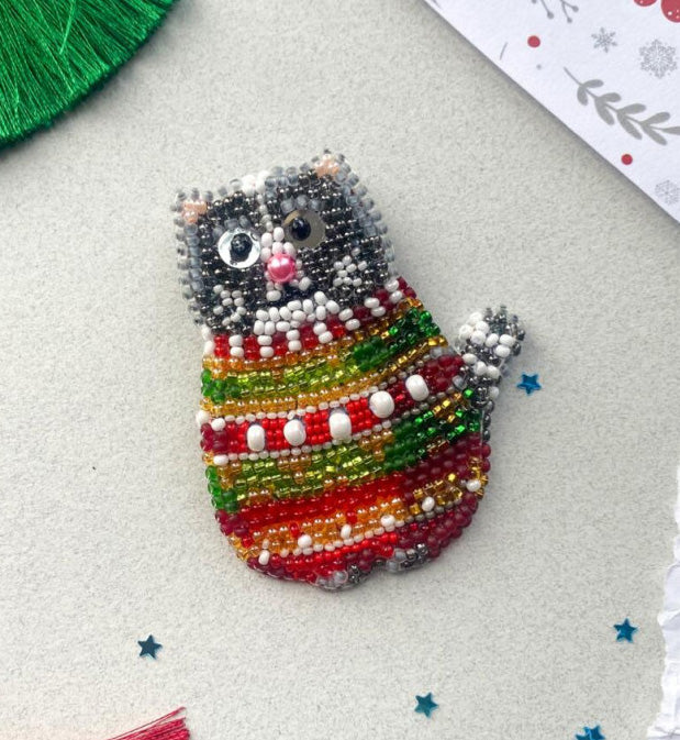 Colorful beaded cat ornament on a textured surface with decorative elements.