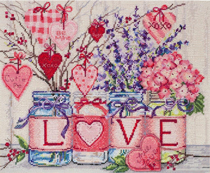 Cross stitch kit depicting a floral design with hearts and the word 'LOVE'Spelt out. Includes various colored threads and fabric, needs a frame for display.