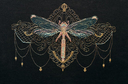 Cross stitch kit depicting a golden dragonfly with ornate details, unprinted canvas, and threads.