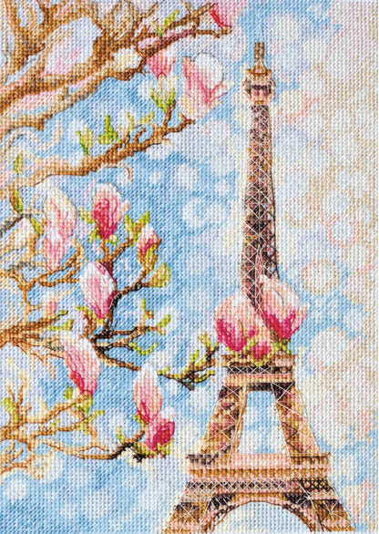A cross stitch kit depicting the Eiffel Tower with magnolia blossoms in the background.