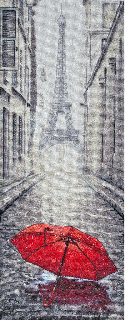 A cross stitch kit depicting a street scene with the Eiffel Tower in the background and a red umbrella in the foreground.