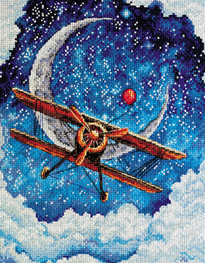 A cross stitch kit depicting a landscape with a airplane, moon, and stars against a night sky, included with threads, fabric, a symbol chart, a needle, and instructions.