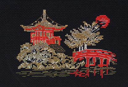 A cross stitch kit depicting a Japanese scene with a red temple, bridge, and green trees on a black background.