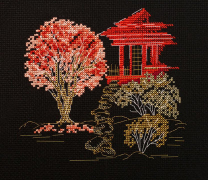 A cross stitch kit depicting a Japanese landscape with a red structure, likely a torii gate, and trees in autumn colors on a black background.