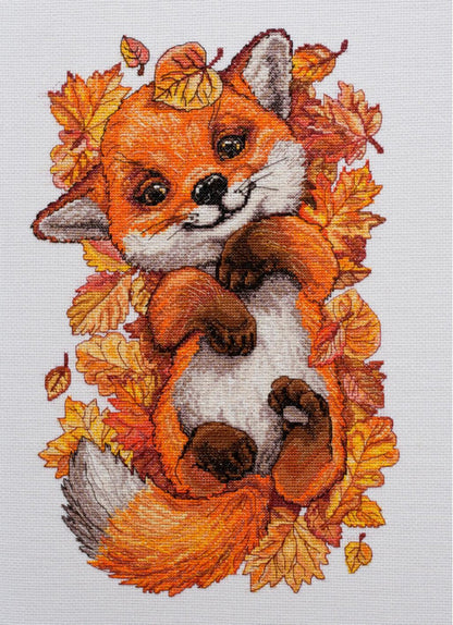 Cross stitch kit depicting a stylized fox surrounded by autumn leaves, with a white background.