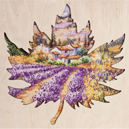 A cross stitch kit depicting a landscape with purple fields, received on a wooden frame.