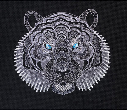 A cross stitch kit depicting the head of a white tiger with blue eyes, primarily in white and gray colors on a black background.