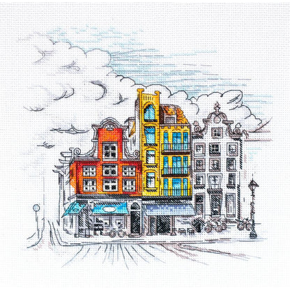 A cross stitch kit depicting a colorful town scene with several buildings and a cloud-filled sky.
