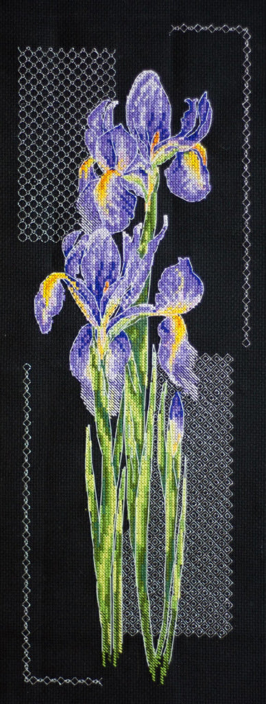 A cross stitch kit depicting a bundle of Japanese irises with purple and yellow flowers on a black background, including Aida fabric and threads.