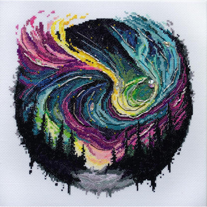 A cross stitch kit depicting a stylized moon and sun design with vibrant colors on a piece of fabric.