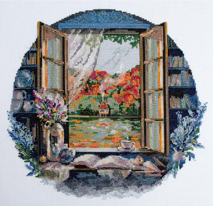 A completed counted cross stitch kit depicting a landscape scene with an open window, books, and a vase of flowers on a windowsill.