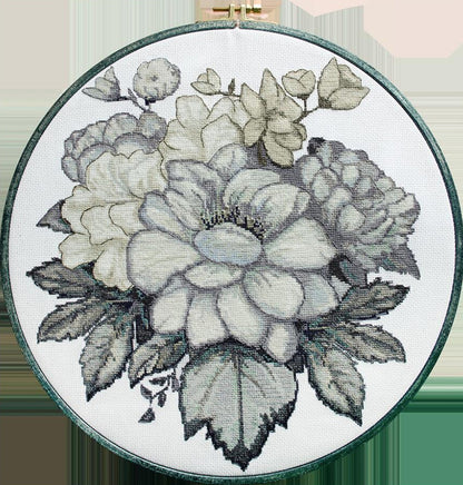 A completed counted cross stitch kit depicting a floral design, displayed in an embroidery hoop.