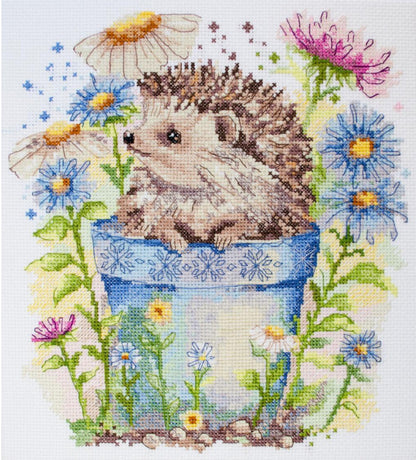 Cross-stitched design of a hedgehog on a blue pot with flowers around it