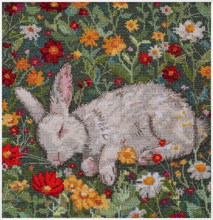 A cross stitch kit depicting a bunny lying in a bed of colorful flowers, with completed stitching shown in the image.