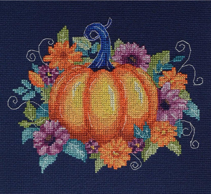 A completed cross stitch kit depicting a pumpkin surrounded by autumn flowers, primarily in orange, yellow, and green colors on a navy background.