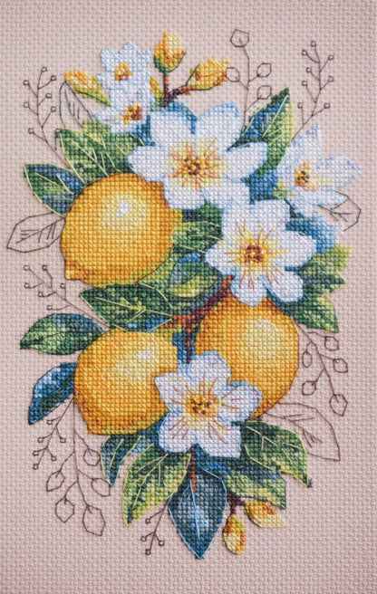 A cross stitch kit depicting a floral design with lemons and blue flowers on a beige background.