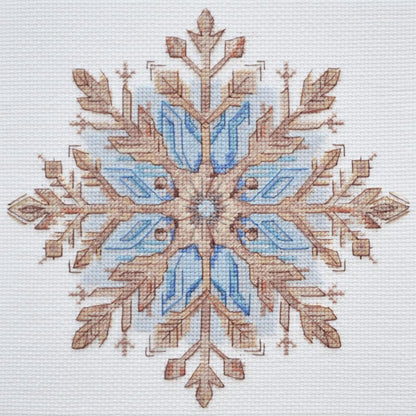 A completed cross stitch kit depicting a blue and beige snowflake on a white background