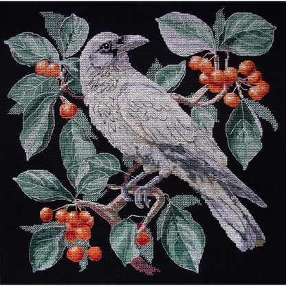 A cross stitch kit depicting a bird perched on a branch with leaves and berries, with black, green, gray, red, and white colors.