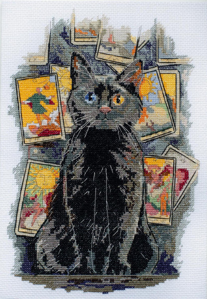 A cross stitch kit depicting a black cat with blue eyes, sitting in front of colorful cards.