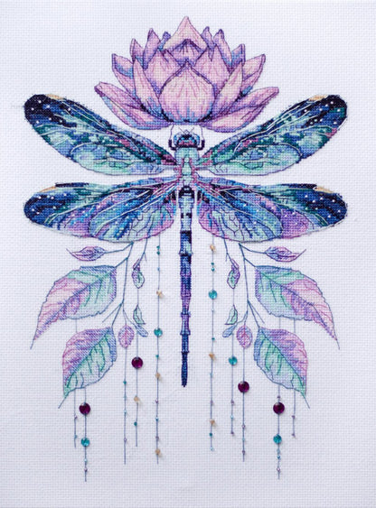 Cross-stitched design of a dragonfly with a lotus flower on a white background