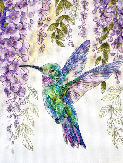 Colorful hummingbird surrounded by wisteria flowers on a cross-stitch pattern