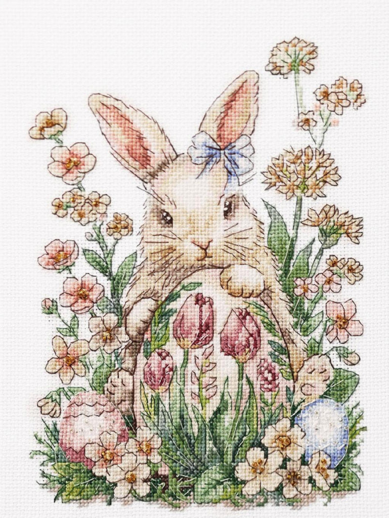 Cross-stitched design of a bunny with flowers and eggs