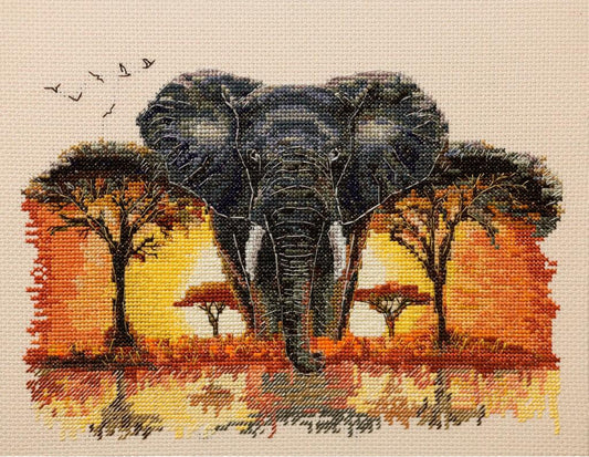A needlepoint canvas featuring a large dark gray elephant walking forward in an African savanna, with orange and yellow acacia trees and a warm sunset sky, on a beige grid background.