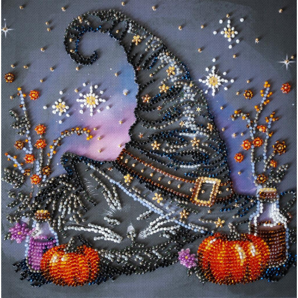 Decorative beaded artwork of a witch with pumpkins and stars on a dark background