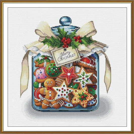 A framed Christmas-themed cross-stitch or needlework-style illustration showing a glass jar filled with gingerbread cookies, decorated with a cream ribbon, green holly, red berries, and a hanging tag that reads “Merry Christmas.”.