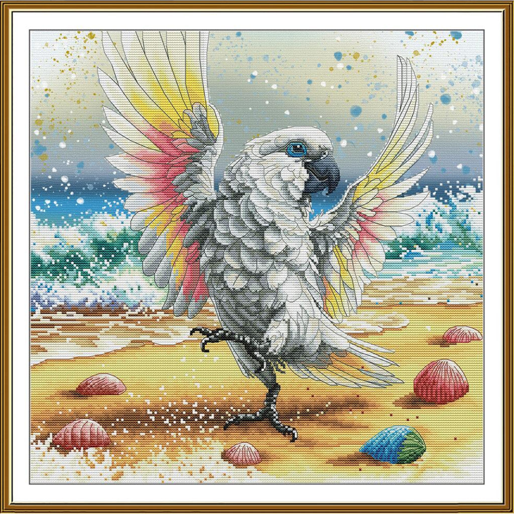 A framed square art print depicting a white cockatoo with spread wings on a sandy beach, with blue ocean waves and shells in the background.