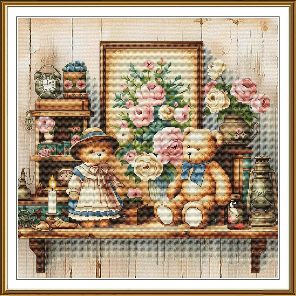 A framed needlepoint or cross-stitch style artwork showing two teddy bears in a rustic room with flowers, shelves, a clock, and a lantern. The central framed floral painting is the most prominent element, and the whole scene is enclosed in a decorative gold-toned frame.