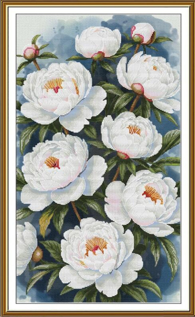 A framed needlepoint or cross-stitch style floral design featuring white peonies with green leaves and small pink buds on a blue watercolor background, enclosed in a gold-toned frame.