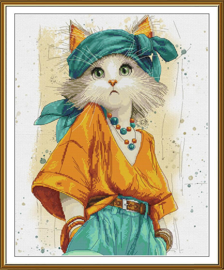 A framed cross-stitch style illustration of a white cat dressed in a teal headscarf, orange top, and teal pants, with a beaded necklace, shown against a cream background with a gold frame.
