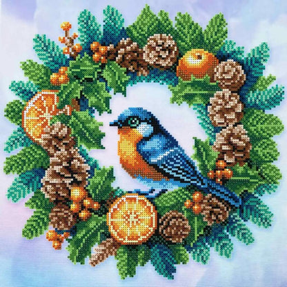 A bead embroidery kit depicting a Christmas wreath with a blue bird, orange slices, and pine cones on a blue background.